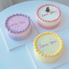 three decorated cakes sitting on top of a white table next to each other with the words love you written on them