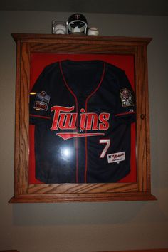 a minnesota twins jersey hangs on the wall above a baseball cap and glove rack in a bedroom