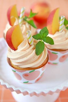 two cupcakes on a plate with apples and mint leaves sticking out of them