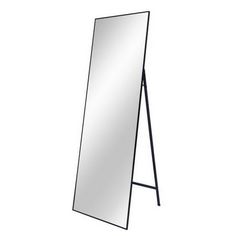 a large mirror sitting on top of a wooden stand next to a white wall with a black frame