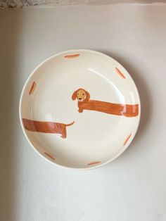 a plate with a dog on it sitting on a table next to a white wall