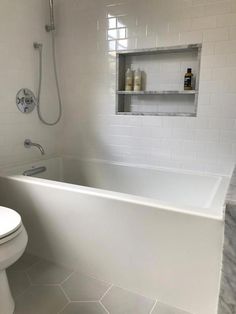 a white bath tub sitting next to a toilet under a shower faucet in a bathroom