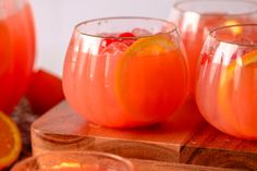 three glasses filled with orange juice on top of a wooden table