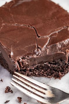 a piece of chocolate cake sitting on top of a white plate next to a fork