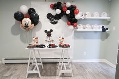 a mickey mouse themed birthday party setup with balloons and decorations on the wall behind it