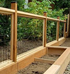 a wooden and metal fence in the middle of some dirt