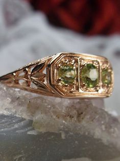 Natural Green Peridot Rose Gold plated Sterling Silver RingLily Design#D197 This is a high-quality Edwardian reproduction filigree ring in rose gold plated sterling silver. This filigree triple stone ring is set with 3 lovely natural green peridot gemstones. The round full cut gem in the center is 4mm. The 2 gems on each side are 2.5mm. The face of the ring is 15.5mm east-west on the finger and 7.5mm north-south on the finger. The inside of the band is marked 925 for sterling silver. Notice the Leaf Filigree, Edwardian Jewelry, 3 Stone Rings, Ring Rose Gold, Peridot Ring, Peridot Gemstone, Green Peridot, Filigree Ring