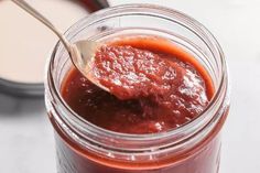 a spoon in a jar filled with red sauce