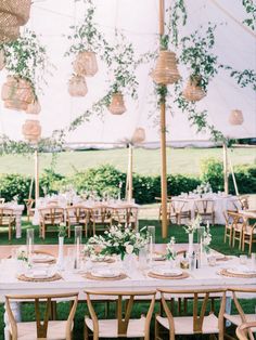 an outdoor tent with tables and chairs set up for a wedding reception in the grass