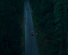 an aerial view of a long road in the middle of some trees at night time