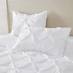 a bed with white sheets and pillows on top of it