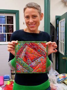 a woman holding up a colorful piece of art