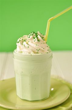 a cup filled with whipped cream and sprinkles on top of a green plate