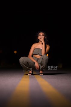 a woman kneeling down in the dark with her hand on her chin and looking up