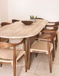 a dining room table with six chairs and a bowl on top of it in front of a white wall