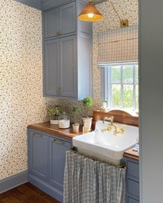 a kitchen with blue cabinets and wallpaper on the walls, along with a white sink