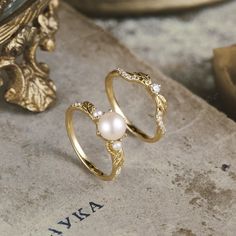 two gold rings with white pearls on top