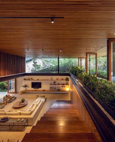 a living room filled with lots of furniture and plants on top of wooden flooring