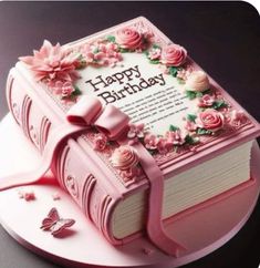 a pink birthday cake decorated with flowers and a book