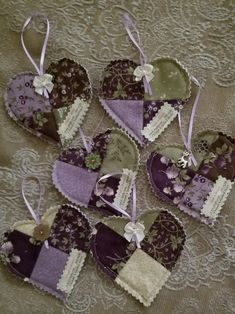 several heart shaped ornaments are arranged on a lace tablecloth with ribbons and tags attached to them