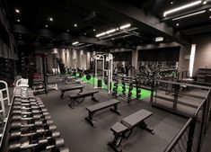 an empty gym with rows of benches and exercise equipment on the floor, all lit up at night