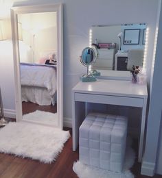 a bedroom with a vanity, mirror and stool