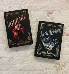 two paperback books sitting on top of a bed next to each other, one is black and the other is red