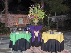 two tables with yellow and green tablecloths are set up in front of a brick wall