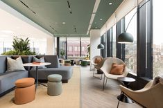 an office with couches, chairs and tables in front of large windows looking out onto the city