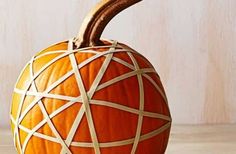 an orange pumpkin decorated with white lines and a wooden stick sticking out of it's side