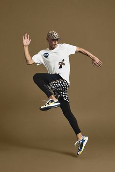 a man jumping in the air while wearing a hat and black leggings with his hands out