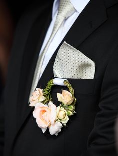 a man in a suit and tie with flowers on his lapel flower is attached to the jacket