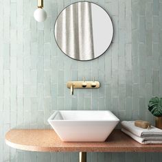 a bathroom sink sitting under a round mirror next to a wall mounted faucet