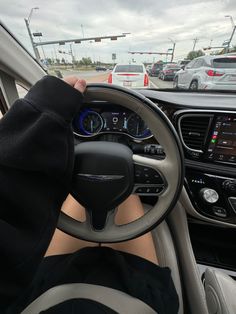 a person in a car with their feet on the steering wheel and hands on the dashboard