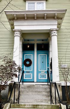 a blue front door with a wreath on it and steps leading up to the entrance