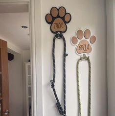 two dog leashes are hanging on the wall with their name and paw prints attached to them