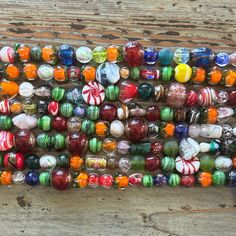 many different colored glass beads are stacked on top of each other in an arrangement with wooden planks