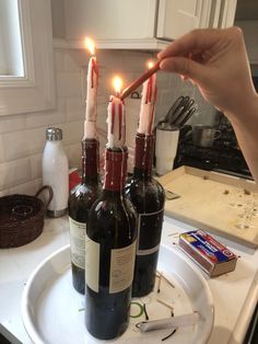 someone is holding candles in their wine bottles