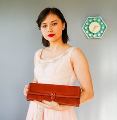 "DESCRIPTION * Vintage purse from 1940s-early 1950s * envelope clutch style: oblong shape, front flap, to be carried \"clutched\" in the hand, strapless * made with reddish-brown leather. I believe it is genuine leather considering its feels, smells, discoloration spots, and texture but there is no tag to confirm this * insert closure * lined with bronze satin fabric * has three small pockets, the largest one has a zippered closure * tag reads \"Lennox\" CONDITION * Minor scratches and discolora Classic Rectangular Evening Bag For Vintage Events, Vintage Evening Bag For Events, Vintage Evening Bag For Vintage Events, Retro Clutch Bag For Vintage Events, Brown Retro Clutch For Formal Occasions, Vintage Envelope Bag For Everyday Use, Retro Clutch For Vintage Events, Vintage Leather Clutch For Evening, Retro Brown Clutch For Evening