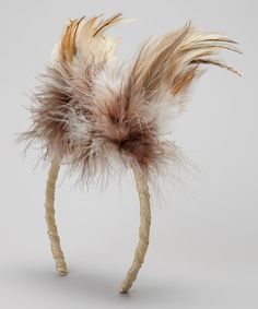 a white and brown feather headband on a gray background