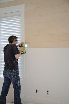 a man is using a driller to paint the walls in his house with white paint