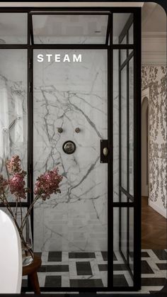 a bathroom with marble walls and flooring next to a bathtub filled with flowers