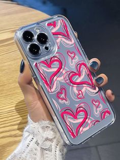 a woman holding up her phone case with hearts on the front and sides, while she is