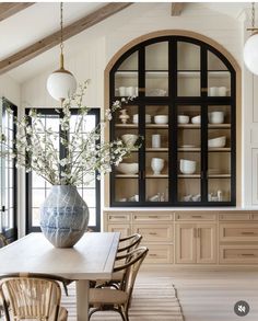 a dining room table with chairs and a vase on it