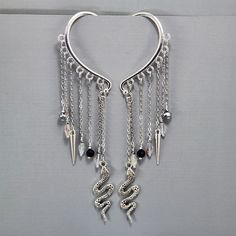 Ear Cuffs Ear Wrap Dangle Ear Cuffs Silver Snake Ear Wrap No Piercing Earrings Clear Glass Crystals Black Glass Crystals Pair or Single I have been making these for a while now.  I can't tell you how much fun these are to create.  The possibilities are endless.  If you ever want a custom design, please reach out to me.   I have embellished these with silver snake charms and silver spikes.  I have used clear and black colored glass crystal beads. They have been wire wrapped for added security.  The chain is plated and will not tarnish.   These will ship in and organza bag perfect for gift giving. Metal Drop Cartilage Earrings For Party, Metal Drop Earrings For Party, Silver Dangle Ear Cuff For Party, Metal Dangle Wrap Earrings For Pierced Ears, Metal Wrap Dangle Earrings For Pierced Ears, Metal Wrap Earrings With Dangle Shape For Pierced Ears, Nickel Free Metal Dangle Ear Cuff, Adjustable Metal Dangle Cartilage Earrings, Adjustable Dangle Cartilage Earrings