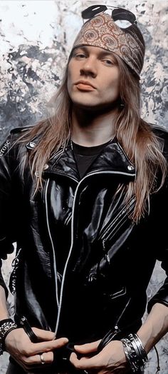 a man with long hair wearing sunglasses and a leather jacket is posing for the camera