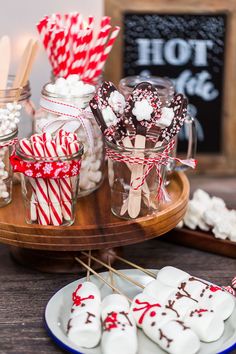 candy and marshmallows are arranged on a table with other sweets in glass jars