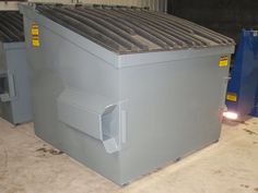 two large metal boxes sitting next to each other on top of a cement floor in a warehouse