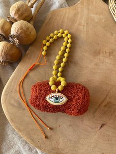 an eyeball bead necklace is displayed on a wooden tray next to garlic bulbs