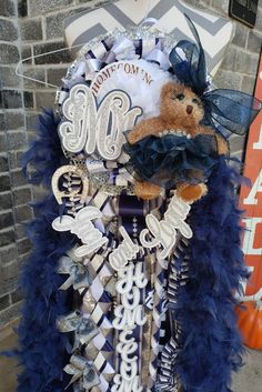 a teddy bear sitting on top of a blue and white dress with feathers around it